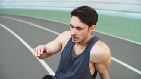 Close-up-of-tired-runner-sitting-on-track-after-running-workout