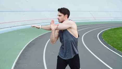 Man-exercising-before-workout-at-sport-stadium.-Guy-runner-warming-up-at-stadium