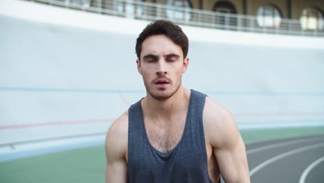 Portrait-of-exhausted-man-training-at-modern-stadium.-Young-man-runner