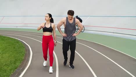 Erschöpftes-Paar-Macht-Pause-Nach-Dem-Gemeinsamen-Training-Auf-Der-Leichtathletikbahn