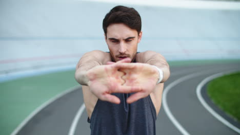 Sportsman-stretching-arms-on-track.-Sport-man-exercising-before-workout-on-track