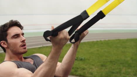 Muscular-man-exercising-with-fitness-rope.-Guy-working-with-fitness-strap