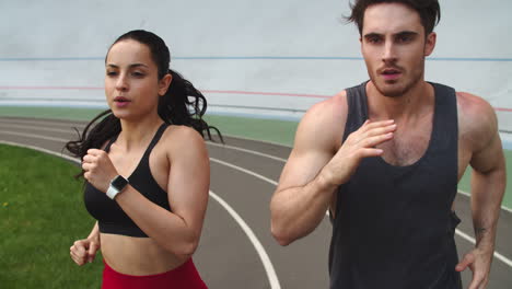 Porträt-Eines-Sportlichen-Paares,-Das-Im-Sportstadion-Läuft.-Fitter-Mann-Und-Frau-Beim-Sprinten