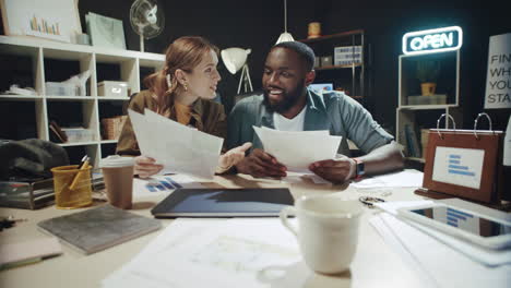 Smiling-afro-man-and-woman-finding-great-information-in-documents-in-office.