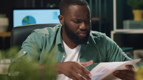 Closeup-disappointed-afro-business-man-looking-papers-in-hipster-office.