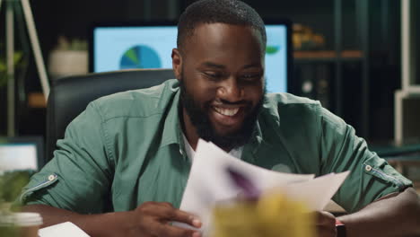 Closeup-satisfied-afro-hipster-guy-looking-at-diagrams-in-hipster-office