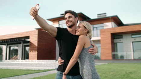 Rich-couple-embracing-near-luxury-apartments.-Selfie-portrait-of-happy-couple