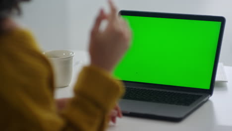 Unrecognized-woman-looking-green-screen-laptop.-Girl-explaining-with-gestures