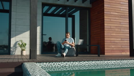 Casual-man-resting-with-mobile-phone.-Handsome-man-using-mobile-at-luxury-house