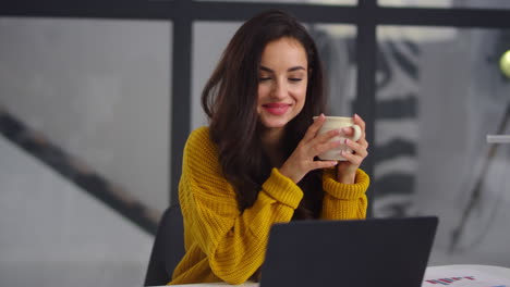 Closeup-business-woman-looking-laptop.-Smiling-girl-drinking-tea-near-notebook