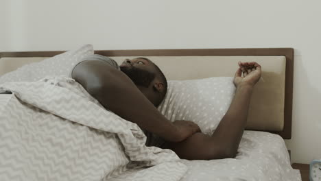 Black-man-waking-up-in-morning-suddenly.-Happy-adult-sitting-in-bed.
