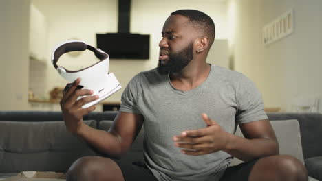 Young-black-man-putting-on-video-glasses-at-kitchen.-Upset-guy-taking-off-vr