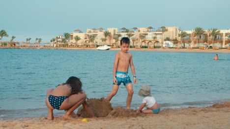 Cute-kids-building-sand-castle-at-sea-bay.-Happy-children-having-fun-at-beach.