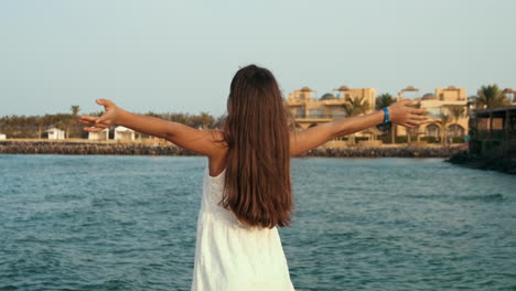 Long-hair-young-woman-enjoying-warm-wind-at-seaside-promenade-at-sea-resort.