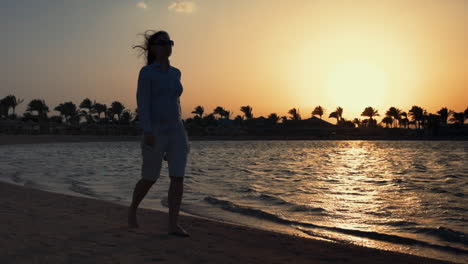 Barefoot-woman-walking-along-coastline.-Pretty-girl-relaxing-at-sunset-beach.