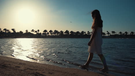Beautiful-woman-walking-along-sea-bay-at-sunset.-Girl-enjoying-vacation-time