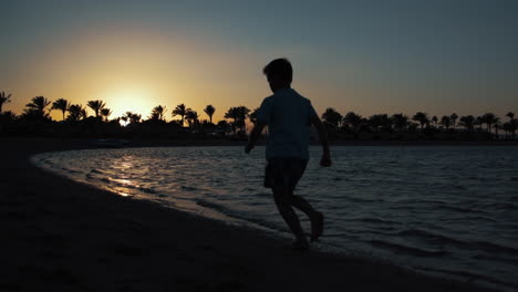 Sporty-young-man-running-near-sea-at-sunset.-Boy-making-workout-on-beach.