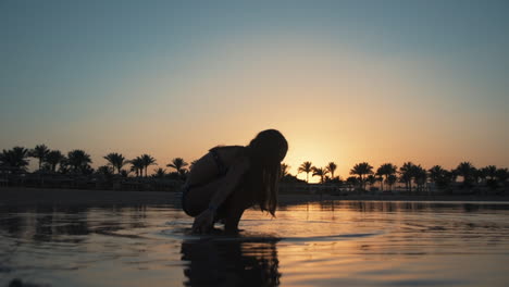 Beautiful-young-woman-relaxing-in-water-at-early-morning-resort-beach.