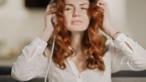 Pretty-woman-putting-headphones-at-open-kitchen.-Joyful-girl-listening-music
