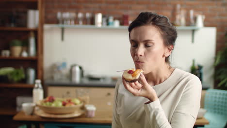 Woman-looking-at-camera-with-fancy-cake-in-hand.-Girl-biting-dessert-at-home.