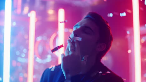 Calm-man-blowing-smoke-in-club.-Relaxed-guy-dancing-under-confetti-at-party
