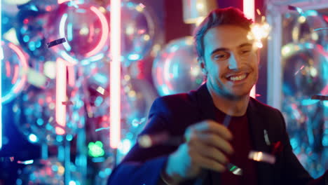 Positive-guy-holding-sparkles-in-nightclub.-Man-dancing-under-confetti