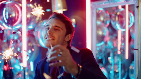 Handsome-man-holding-sparkles-at-party.-Guy-dancing-with-bengal-lights-in-club