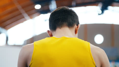 Athlete-in-yellow-form-preparing-for-performance.-Back-of-man-in-sports-shirt