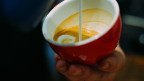 Man-holding-cup-with-aromatic-coffee-and-adding-milk.-Barista-cooking-latte