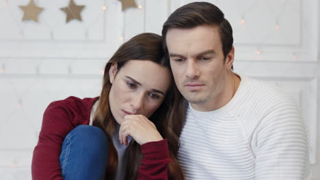 Portrait-of-thinking-couple-sitting-in-living-room.-Sad-lady-lying-man-shoulder
