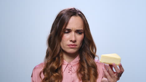 Sad-woman-looking-at-cake-in-hand.-Upset-woman-holding-piece-of-cheesecake
