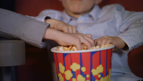 Manos-De-Niños-Tomando-Palomitas-De-Maíz-De-Una-Caja-De-Papel.-Comida-De-Cine-Para-Niños