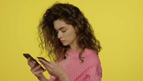 Young-woman-using-money-apps-in-smartphone-for-pay-bank-card-in-yellow-studio