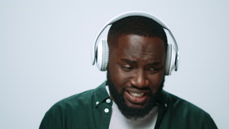 Closeup-smiling-african-guy-listening-music-in-earphones-on-grey-background.