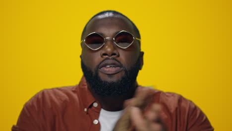 Portrait-of-serious-african-man-showing-cross-hand-in-yellow-background.