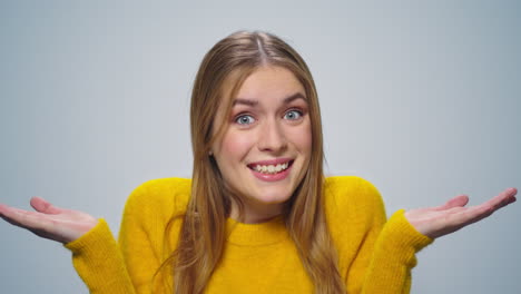 Portrait-of-smiling-attractive-woman-shrugging-shoulders-on-grey-background.