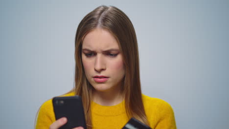 Portrait-of-serious-girl-shopping-online-on-smartphone-on-grey-background.