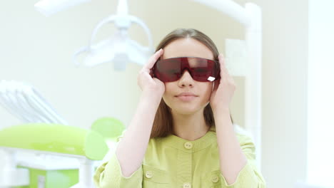 Female-dentist-dressing-up-ultraviolet-orange-safety-goggles.-Woman-doctor