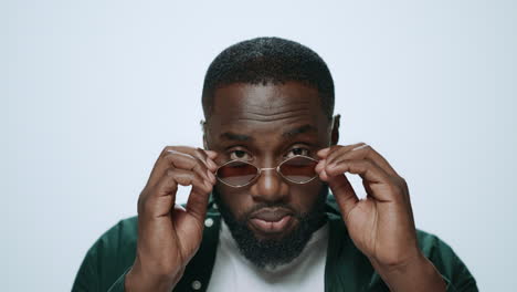 Portrait-of-ambitions-african-man-putting-sunglasses-in-grey-background.