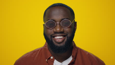 Retrato-De-Un-Hombre-Afroamericano-Sonriendo-A-La-Cámara-Sobre-Fondo-Amarillo.