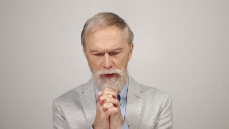 Stressed-man-praying-indoors.-Aged-sad-guy-shaking-hands-in-studio-background.