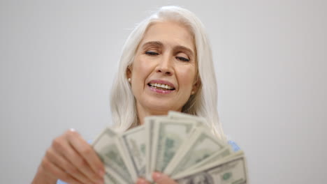 Rich-aged-woman-counting-money-in-studio.-Successful-lady-holding-cash-indoors.