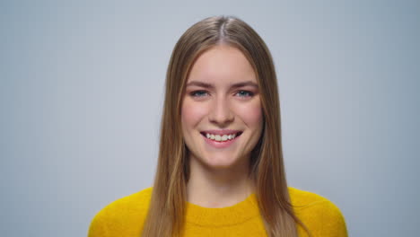 Closeup-beautiful-happy-woman-smiling-at-camera-on-grey-background-in-studio.