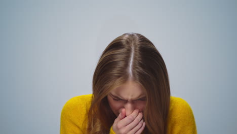 Portrait-of-beautiful-ill-girl-sneezing-at-camera-on-grey-background.