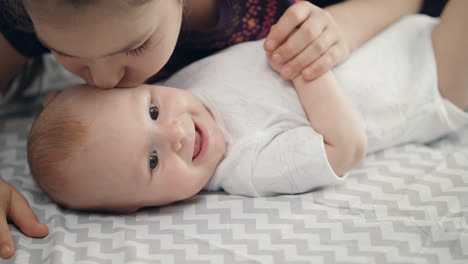 Sister-love-concept.-Infant-baby-smiling-from-sister-kiss.-Lovely-childhood