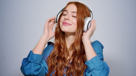 Smiling-girl-listening-music-indoors.-Relaxed-woman-making-movements-in-studio
