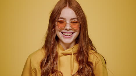 Charming-girl-smiling-in-studio.-Woman-posing-at-lens-on-orange-background