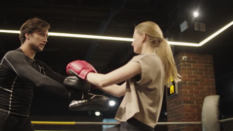 Agitated-sport-woman-practicing-leg-hits-on-boxing-ring.-Fit-girl-boxing-at-gym
