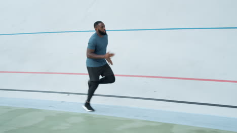 Young-man-running-on-sport-track-at-stadium.-Active-athlete-jogging-outdoors