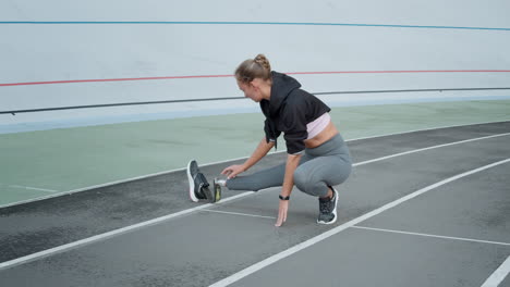 Disabled-fit-woman-stretching-legs-on-track.-Lady-preparing-for-workout-outdoors